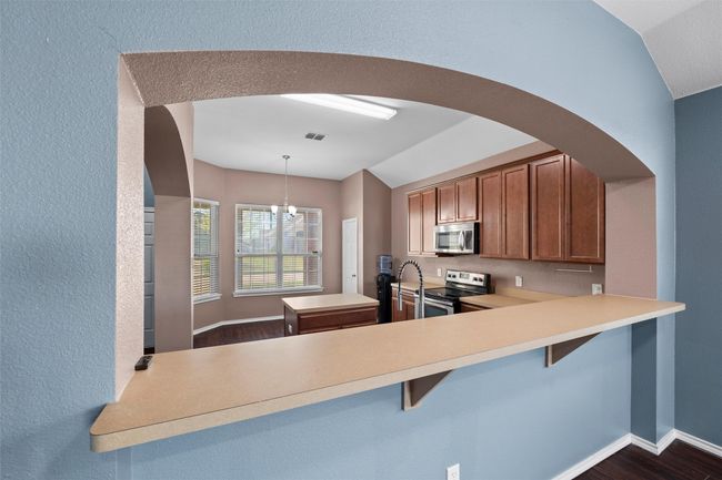 Kitchen featuring visible vents, arched walkways, a notable chandelier, appliances with stainless steel finishes, and vaulted ceiling | Image 12