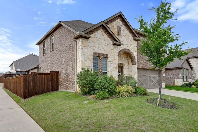 French country home with stone siding, concrete driveway, a garage, and brick siding | Image 4