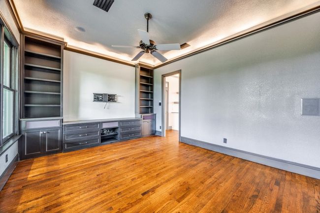 Unfurnished living room featuring wood finished floors, a ceiling fan, and built in shelves | Image 11