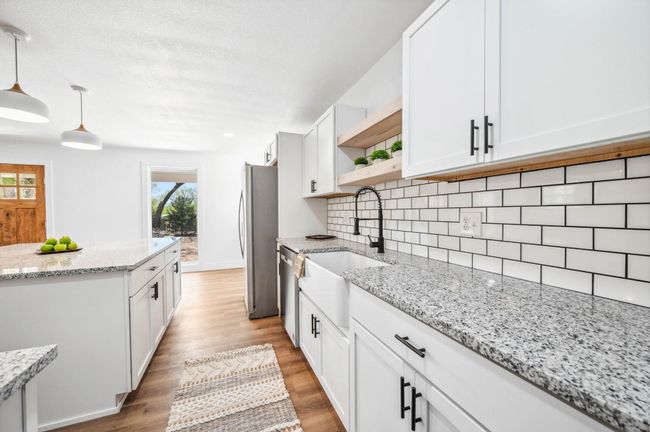 Kitchen featuring open shelves, a sink, appliances with stainless steel finishes, light wood-style floors, and backsplash | Image 11