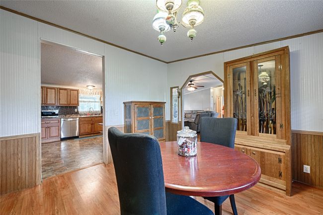 Dining area with wood walls, a wainscoted wall, light wood-style floors, ornamental molding, and a chandelier | Image 16