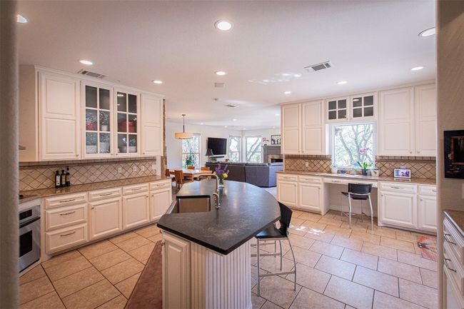 Kitchen with stainless steel oven, decorative backsplash, a kitchen breakfast bar, open floor plan, and light tile patterned flooring | Image 12