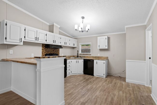 Kitchen featuring dishwasher, light wood finished floors, a chandelier, a peninsula, and white cabinetry | Image 17