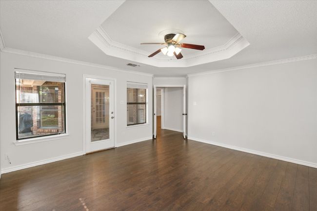 The primary bedroom not only has several windows with two inch blinds, but it also has a door leading to the covered flagstone patio. | Image 31