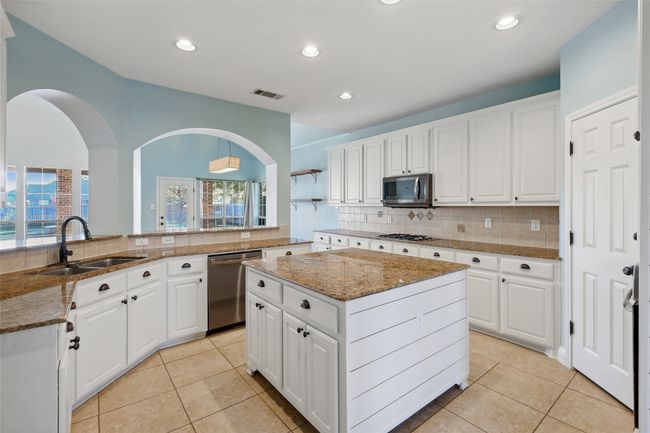 Kitchen featuring a center island, white cabinetry, sink, and appliances with stainless steel finishes | Image 13