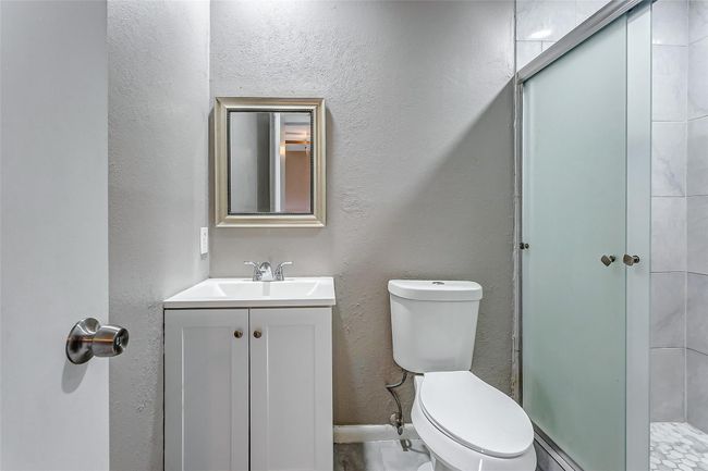 This elegant bathroom features a modern vanity with clean lines, a sleek frameless mirror, and contemporary fixtures. The frosted glass shower door adds a touch of sophistication while ensuring privacy. Perfectly designed for both form and function, this bathroom is an oasis of relaxation. | Image 18
