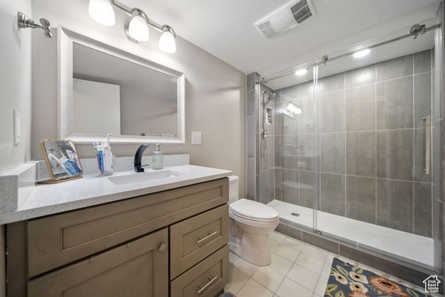 Bathroom with toilet, vanity, a shower stall, and tile patterned floors | Image 24