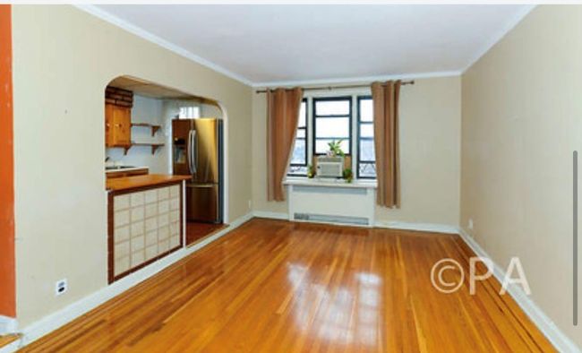 Unfurnished living room featuring arched walkways, wood finished floors, baseboards, and ornamental molding | Image 7