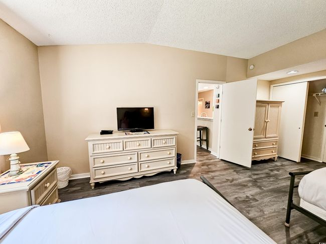 Bedroom with dark wood-type flooring, a textured ceiling, baseboards, and vaulted ceiling | Image 28