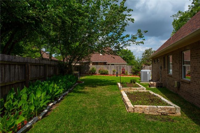 View of yard featuring a fenced backyard, central AC unit, and a vegetable garden | Image 39