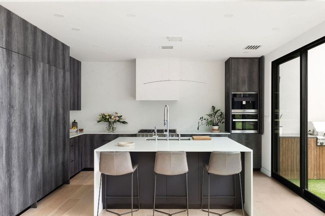 Kitchen featuring modern cabinets, light wood-style floors, a sink, light countertops, and a kitchen island with sink | Image 13