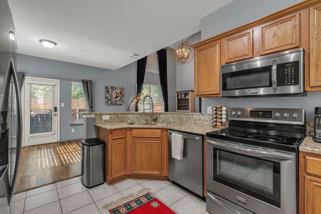 Kitchen with appliances with stainless steel finishes, a peninsula, brown cabinetry, and a chandelier | Image 9