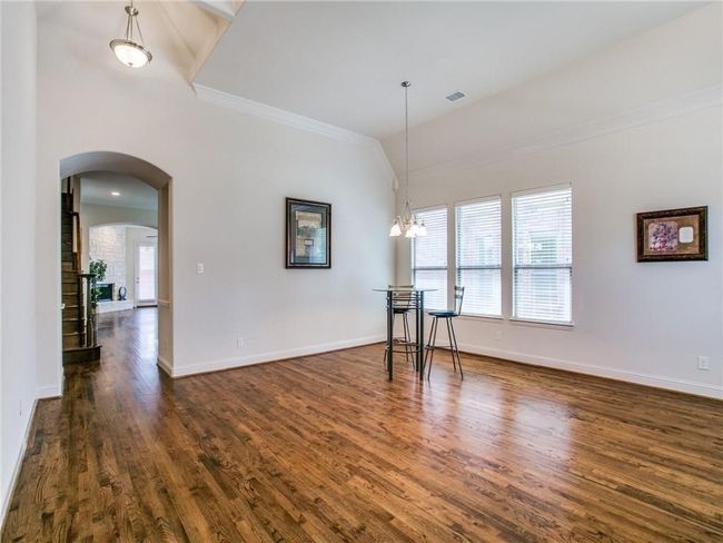 Spare room with arched walkways, crown molding, plenty of natural light, dark wood-type flooring, and baseboards | Image 5