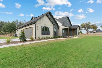 Modern inspired farmhouse featuring a front yard, central AC unit, and a garage | Image 2