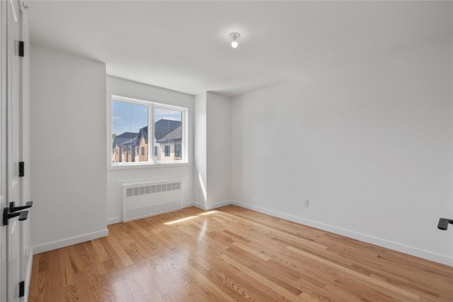 Spare room featuring radiator heating unit, baseboards, and light wood-type flooring | Image 31