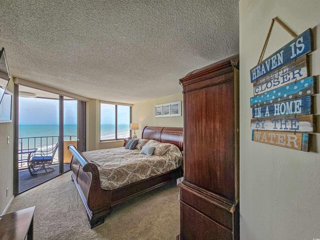 Bedroom featuring access to exterior, carpet floors, a textured ceiling, and a water view | Image 21