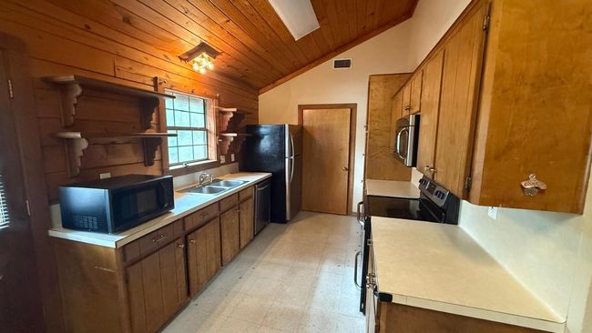 Kitchen featuring a sink, wooden ceiling, open shelves, vaulted ceiling, and appliances with stainless steel finishes | Image 11