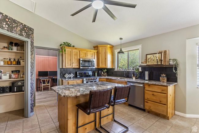 Kitchen with stainless steel appliances, a center island, decorative backsplash, ceiling fan, and pendant lighting | Image 5
