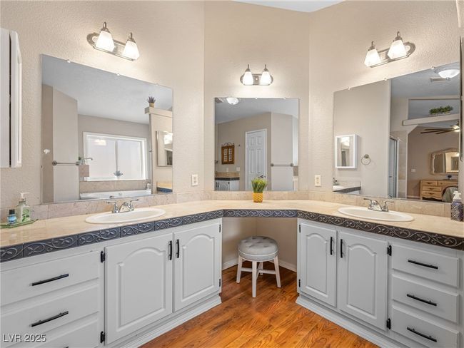 Bathroom with an enclosed shower, vanity, a textured wall, and wood finished floors | Image 35