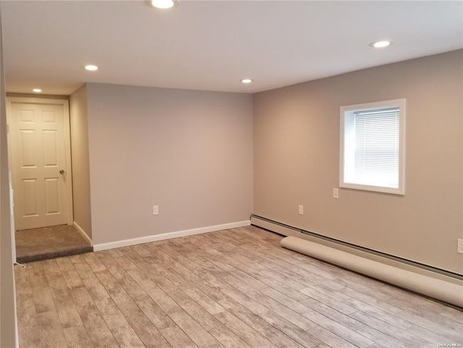 Unfurnished room with a baseboard heating unit, light wood-type flooring, recessed lighting, and baseboards | Image 12