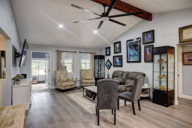 Living area with light vinyl finished floors, recessed lighting, a ceiling fan, beamed ceiling, and high vaulted ceiling | Image 9
