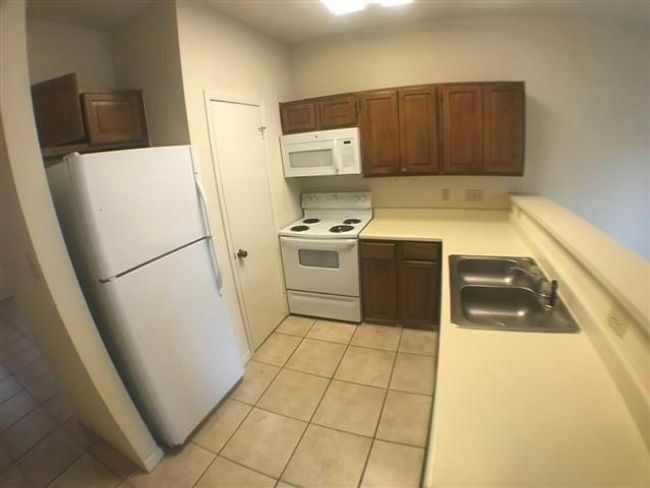 Kitchen featuring light countertops, a sink, light tile patterned floors, and white appliances | Image 6