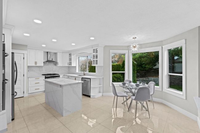 Kitchen featuring tasteful backsplash, white cabinets, wall chimney exhaust hood, and stainless steel appliances | Image 12