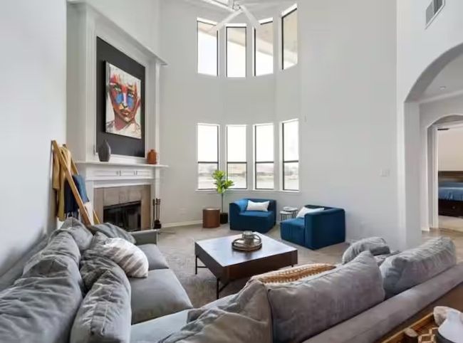 Carpeted living area featuring arched walkways, a high ceiling, and a tiled fireplace | Image 8
