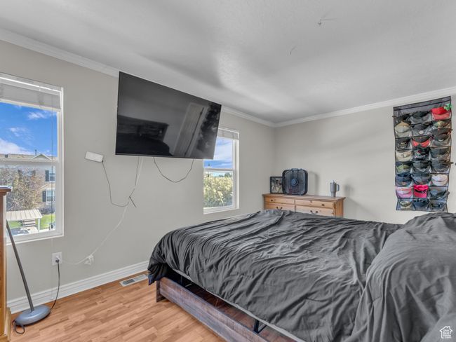 Bedroom with baseboards, light wood-style flooring, and crown molding | Image 23