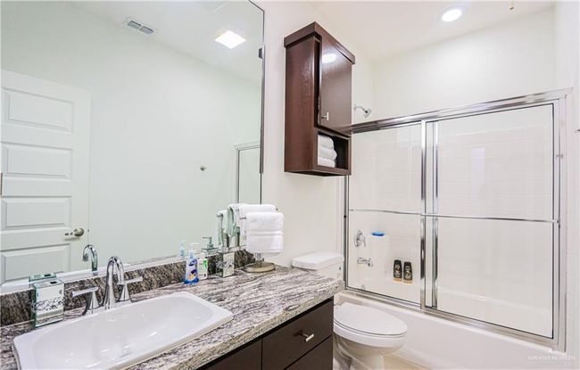 Full bathroom with shower / bath combination with glass door, vanity, and toilet | Image 23