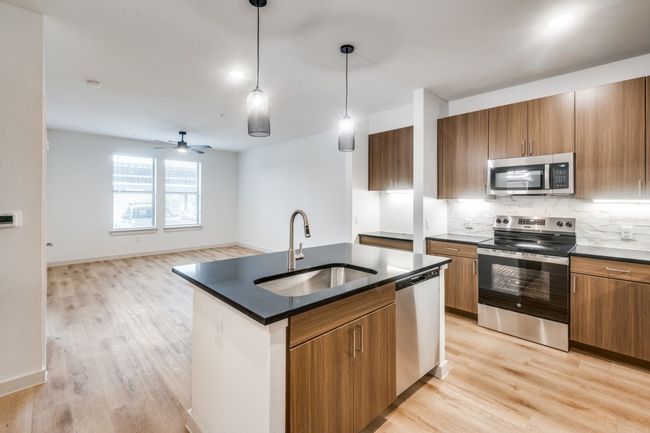 Kitchen featuring dark countertops, brown cabinetry, appliances with stainless steel finishes, and a​​‌​​​​‌​​‌‌​‌‌​​​‌‌​​‌‌​‌​​​​​‌ sink | Image 7