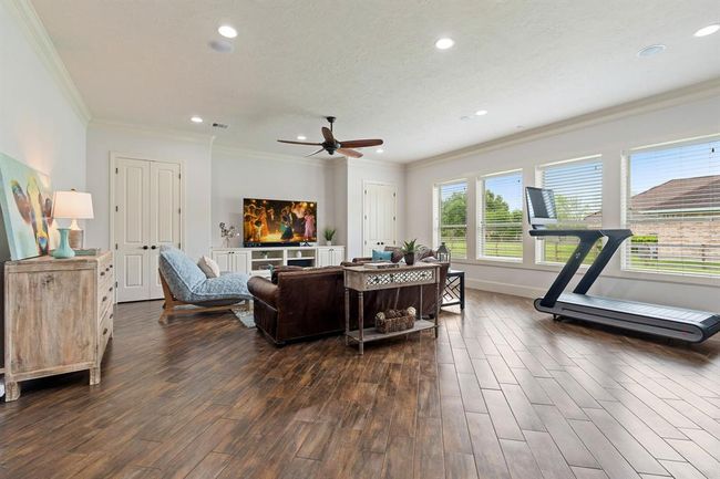 Tucked away in its own wing of the home sits this spacious Game Room. Wood-like tile flooring makes floor clean up a breeze while crown molding, extra-wide baseboards, and recessed lighting really dress up the space. Two closets help keep the room tidy by providing a home for games, toys, and accessories. | Image 31