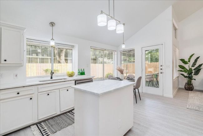 Kitchen featuring healthy amount of natural light, decorative light fixtures, white cabinets, a kitchen island, and vaulted ceiling | Image 11