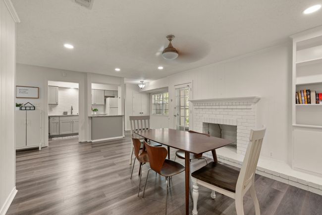 Dining room featuring dark wood-style flooring, baseboards, recessed lighting, a brick fireplace, and crown molding | Image 12
