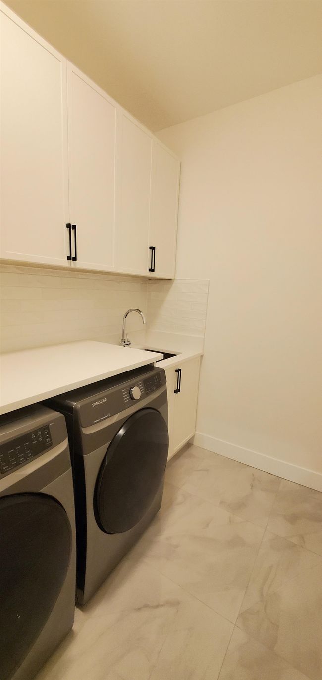 Laundry room featuring cabinet space, a sink, marble finish floor, baseboards, and washer and clothes dryer | Image 6