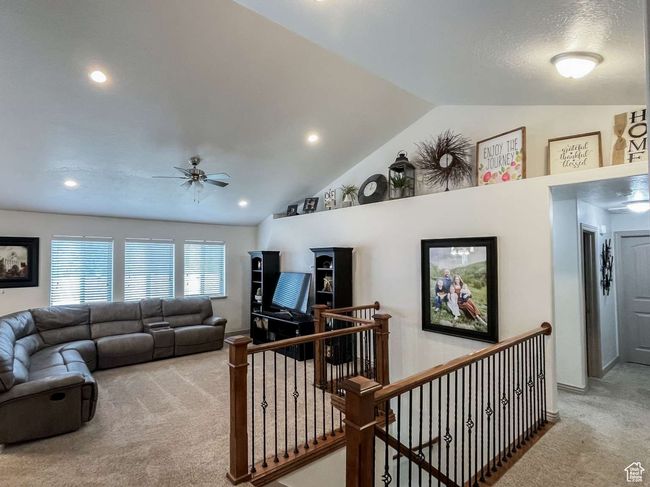 Carpeted living area featuring lofted ceiling, a ceiling fan, and recessed lighting | Image 13