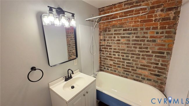 Bathroom with shower / bath combination, vanity, and brick wall | Image 4