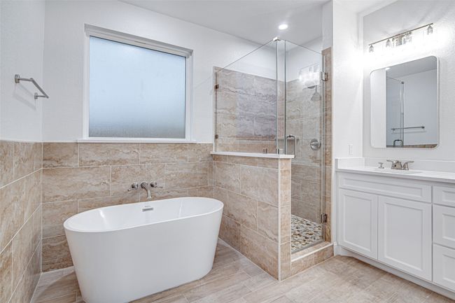 Full bathroom featuring tile walls, a shower stall, a freestanding bath, vanity, and a wainscoted wall | Image 26