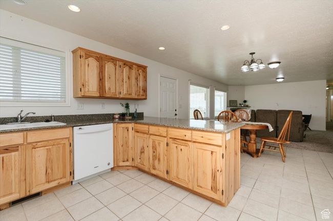 Kitchen featuring white dishwasher, open floor plan, a chandelier, a peninsula, and light tile patterned flooring | Image 40