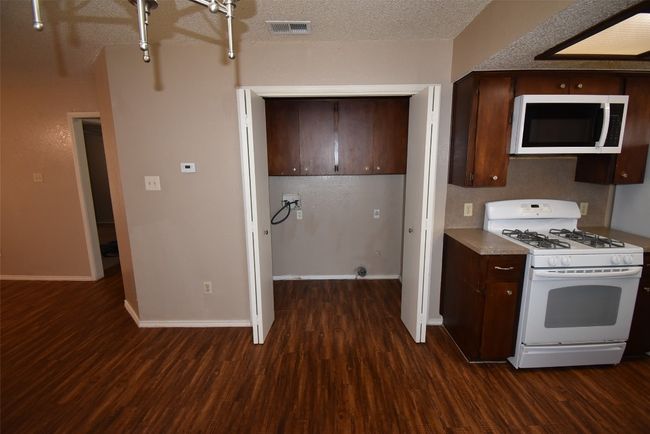 Kitchen with white appliances, dark wood-style floors, dark brown cabinets, and a textured ceiling | Image 6