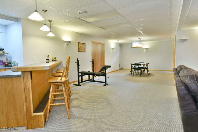 Indoor dry bar with carpet flooring, a paneled ceiling, baseboards, and decorative light fixtures | Image 39