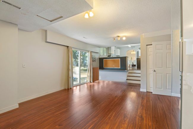 Unfurnished living room with a textured ceiling, wood finished floors, visible vents, and stairway | Image 13
