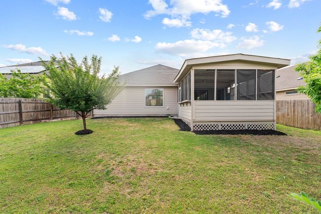 Back of property with a fenced backyard, a sunroom, and a lawn | Image 16