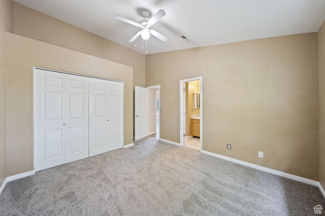 Unfurnished bedroom featuring light colored carpet, a closet, lofted ceiling, ceiling fan, and ensuite bathroom | Image 24