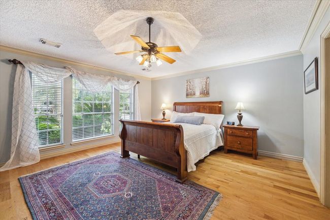 This inviting primary bedroom features custom hardwood floors and a large window for plenty of light. | Image 15
