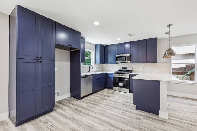 Kitchen with stainless steel appliances, a peninsula, light countertops, baseboards, and recessed lighting | Image 13