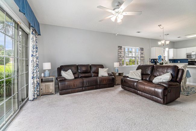 Living area with carpet, a ceiling fan, and sliding glass door to outside. | Image 7