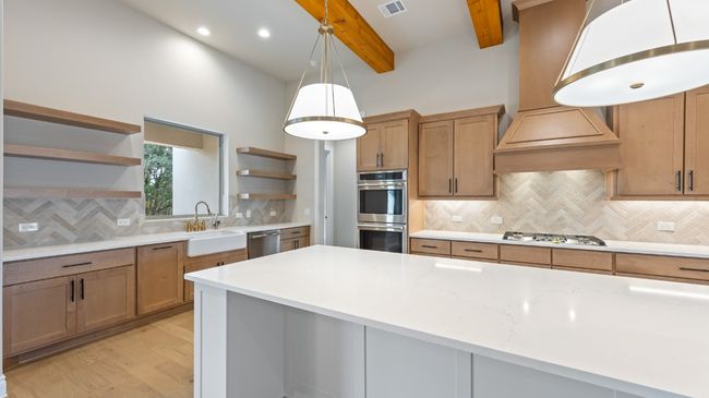 Kitchen with open shelves, decorative backsplash, light stone counters, light wood-style flooring, and stainless steel appliances | Image 17