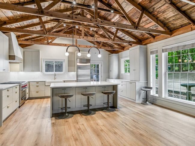 Kitchen with light wood-style flooring, high quality appliances, a kitchen island, premium range hood, and a sink | Image 6
