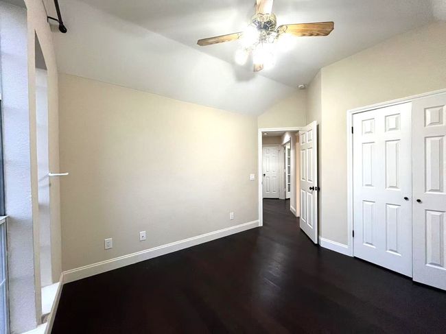 Unfurnished bedroom with vaulted ceiling, dark wood-style floors, a closet, and ceiling fan | Image 24